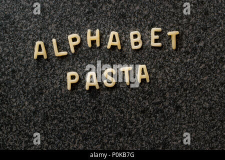 Materie alfabeto Pasta è scritto con lettere su Granit superficie grigia. Non cotti gli alimenti biologici. Foto Stock