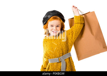 Sorridente capelli rossi bambino holding shopping bag in mano isolato su bianco Foto Stock