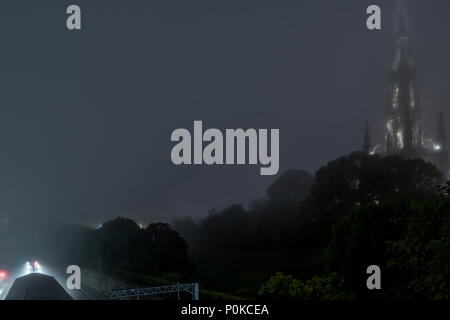 Scott del monumento di notte con una fitta nebbia di mare facendo una misteriosa scena nel centro di Edimburgo con la stazione di Waverley sulla sinistra Foto Stock