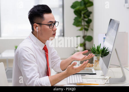 Architetto in ufficio a parlare al cliente sul telefono con gli auricolari Foto Stock