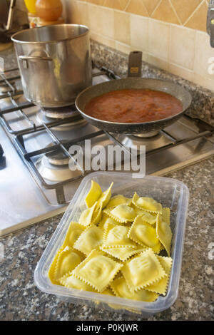 La preparazione di ravioli con salsa di pomodoro su un piano cottura Foto Stock