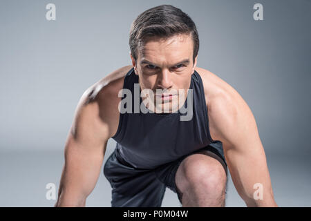 Fiducioso sportsman ottenere pronto per lavorare su uno sfondo grigio Foto Stock