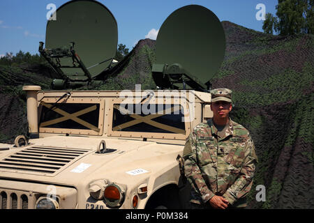 Stati Uniti Army Spc. Antonio Perez Gonzalez, un sicuro Anti-Jam Mobile affidabile terminale tattico o SMART-T, operatore assegnato alla società di Charlie, 44th Expeditionary Battaglione di segnale, 2° segnale teatro brigata, sorge accanto alla SMART-T fornendo supporto di comunicazioni di esercitare Saber Strike, Giugno 4, 2018 vicino a Powidz, Polonia. Saber Strike è un U.S. Esercito Europa-led esercizio di circa 18.000 soldati provenienti da 19 nazioni partecipanti luogo in Lituania, Estonia, Lettonia e Polonia da Giugno 3-15, 2018. (U.S. Foto dell'esercito da William B. King) Foto Stock