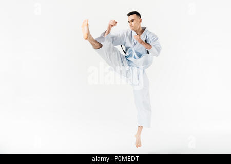 Maschio combattente di karate di eseguire kick isolato su bianco Foto Stock