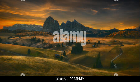 Vista di legno tradizionali chalet di montagna su SCENIC Alpe di Siusi con Sassolungo montagna a sunrise, Dolomiti, Alto Adige, Italia Foto Stock