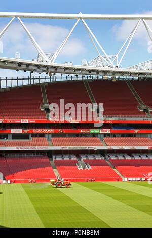 Un trattore rivestimenti l'erba sul passo in corrispondenza della Londra Emirates Stadium, casa Premier League football team Arsenal. Foto Stock