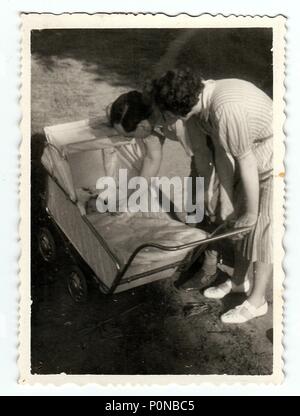 HODONIN, la Repubblica cecoslovacca, circa 1940: Vintage foto mostra la bambina in una carrozzina (carrozzina) con i genitori, circa 1940. Foto Stock