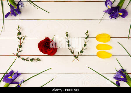 Vista superiore della parola amore realizzati da elementi floreali e bellissimi fiori iris sulla superficie di legno Foto Stock