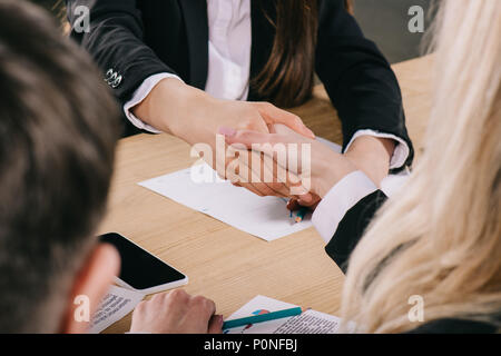 Vista ritagliata di due imprenditrici stringono le mani a tavola in office Foto Stock