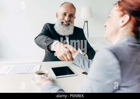 Senior happy business partner stringono le mani in un ufficio moderno interno Foto Stock