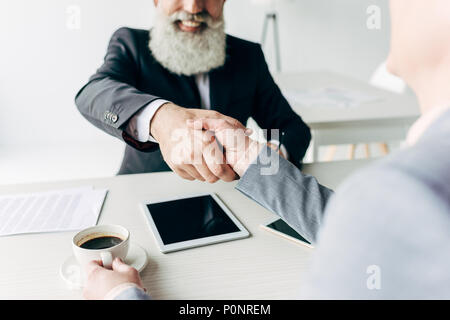 Senior happy business partner stringono le mani in un ufficio moderno interno Foto Stock