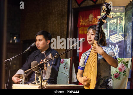 Suzhou, Jiangsu, Cina. Giovane donna giocando una pipa, Giovane giocando un 'tre stringhe". Foto Stock