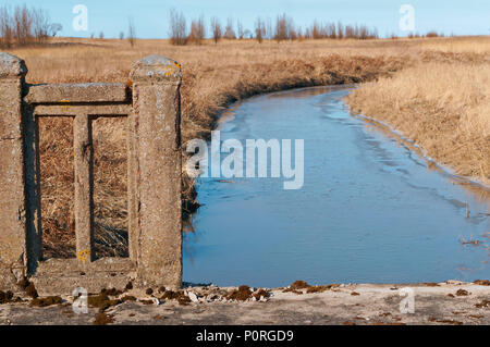 Il fiume nel campo in autunno, distrutto il vecchio ponte di cemento sul fiume Foto Stock