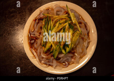 Cucina uigura: handmade noodle con insalata di cetrioli freschi con condimento al Peperoncino condito con aglio fritto Foto Stock