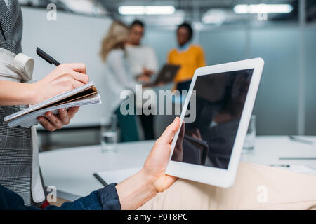 Imprenditore azienda tablet con schermo vuoto in un ufficio moderno mentre collega rendendo note Foto Stock