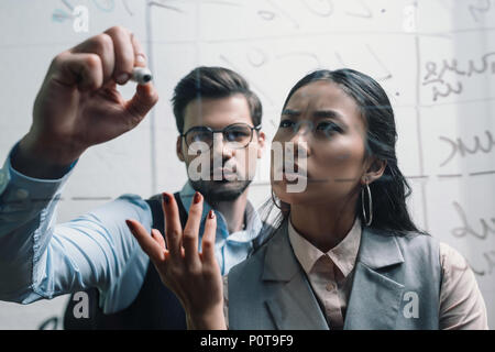 Imprenditore e imprenditrice asiatici la scrittura sulla scheda di vetro in office Foto Stock