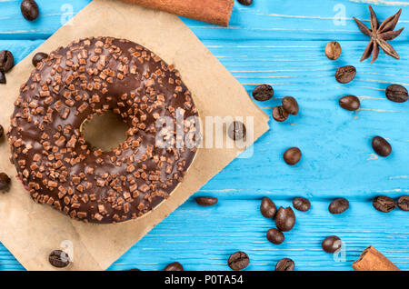 Ciambella di cioccolato con sparsi grani di caffè e spezie su uno sfondo di legno, vista dall'alto Foto Stock