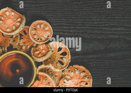 Le erbe aromatiche essiccate e secchi Frutta bael, vista dall'alto di bael asciutto e bicchiere di tè e succhi bael sul pavimento di legno, fette di frutta bael sul tavolo scuro. Foto Stock