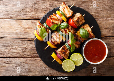Hot pollo grigliato kebab spiedini con verdure colorate con salsa, basilico e calce closeup sul tavolo. Parte superiore orizzontale vista da sopra Foto Stock