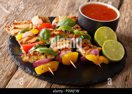 Hot pollo grigliato kebab spiedini con verdure colorate con salsa, basilico e calce closeup sul tavolo orizzontale. Foto Stock