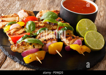 Grigliate gli spiedini di pollo con verdure estive con salsa, basilico e calce closeup sul tavolo orizzontale. Foto Stock