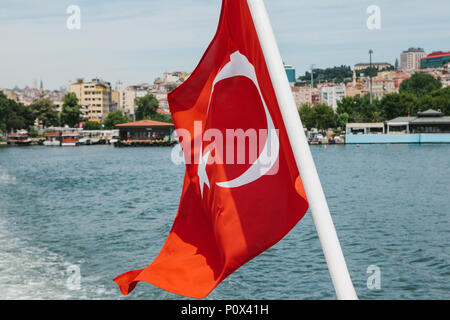 La nazionale turca sventola bandiera nel vento contro lo sfondo del Bosforo e Istanbul sfocati in background Foto Stock