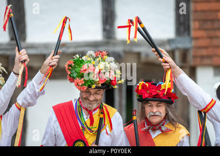 Morris ballerini indossando cappelli estivi coperto di fiori e indossando costumi tradizionali ballare durante una morris dancing evento nel West Sussex, in Inghilterra. Foto Stock