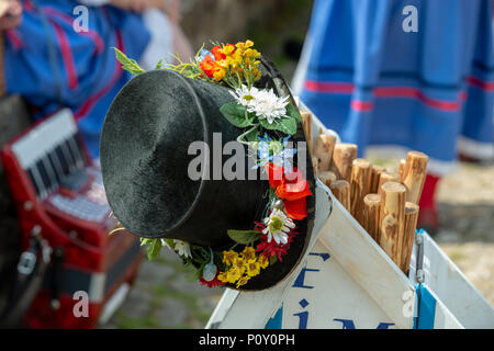 Un black top hat ricoperto di fiori colorati e indossato da un ballerino di morris poggia su un camion di legno durante una pausa nella danza a morris dancing evento nel West Sussex, in Inghilterra, Regno Unito. Foto Stock