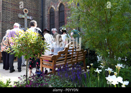 Le persone che frequentano la dedicazione di un nuovo memorial garden a San Clemente Chiesa, Notting Dale, West London in occasione del primo anniversario del disastro Grenfell. Foto Stock