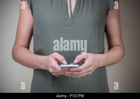 Le mani di una donna adulta che tiene in mano uno smartphone, mette in mostra social media e reti digitali, background ideale per la comunicazione e la tecnologia moderna Foto Stock