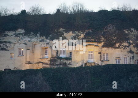 Illuminato di alloggiamento troglodita e cantina facciata costruito nella collina sopra il vigneto nella Valle della Loira, Francia Foto Stock
