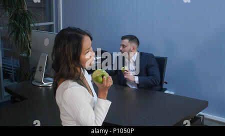 I giovani uomini di affari a pranzo insieme, mangiare mela verde Foto Stock