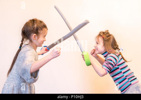 Due ragazze con le spade giocattolo giocare cavalieri. I bambini le emozioni Foto Stock