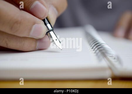 Man mano con penna che scrive su notebook, primo piano Foto Stock
