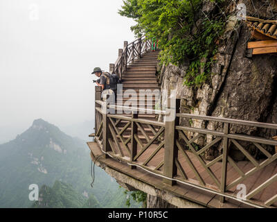 25 Maggio 2018: un fotografo preparando per scattare fotografie presso la scogliera appendere la passerella a Tianmen Mountain, il cielo's Gate a Zhangjiagie Hunan P Foto Stock