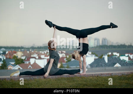Due giovani donne ginnasti facendo acrobazie elementi con il paesaggio sullo sfondo Foto Stock