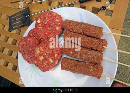 Pericolo di intossicazione alimentare da estate barbecue di carne e salumi, hamburger, spiedini, sotto-cotto o crudo Foto Stock