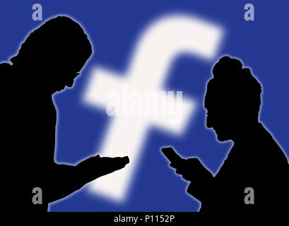 Sagome di un paio di persone utilizzando la app Facebook su smartphone. Foto Stock