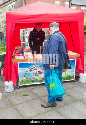 L'uomo cliente in Saltburn Farmers Market guardando un display di salsicce da Free Range outdoor allevati suini Foto Stock