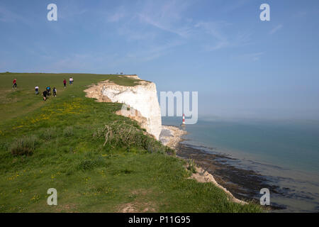 I turisti a piedi vicino al bordo della scogliera e del faro di Beachy Head, Eastbourne, Chalk promontorio in East Sussex, England, Regno Unito Foto Stock