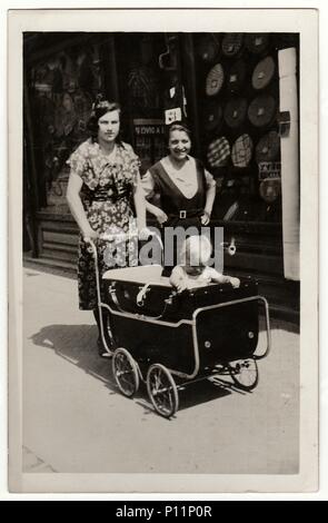 HODONIN, la Repubblica cecoslovacca - circa 1945: un vintage mostra fotografica di donne andare per una passeggiata con la PRAM baby carrello . Antico bianco nero photo. Foto Stock