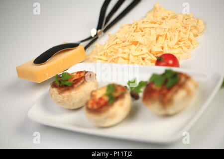 Formaggio grattugiato accanto a una piastra con le teste a fungo Foto Stock