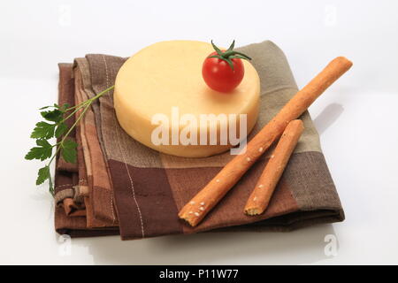 Formaggio di piccole dimensioni ruota accanto a pomodori ciliegia Foto Stock