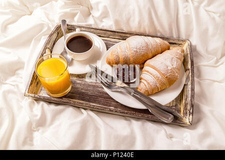 La deliziosa prima colazione a letto con caffè e croissant. Foto Stock