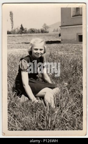 La REPUBBLICA SOCIALISTA CECOSLOVACCA - circa sessanta: Vintage foto mostra la ragazza si siede sull'erba. Foto Stock