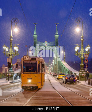 Passaggio di un tram conducente dà un pollice in alto su una coperta di neve Ponte della Libertà a Budapest Foto Stock