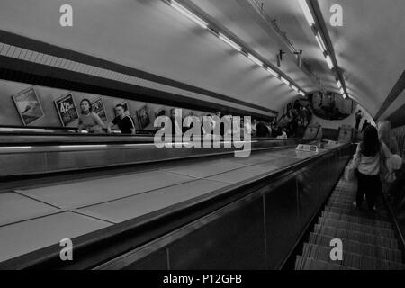 Immagine in bianco e nero di persone sulle scale mobili in metropolitana di Londra, Regno Unito - Concetto / storia immagine Foto Stock