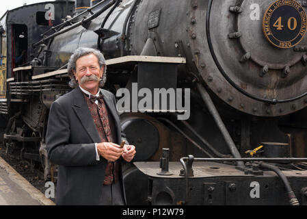 Una guida turistica, vestito come Mark Twain, pone accanto alla Essex treno a vapore in Essex Connecticut Foto Stock