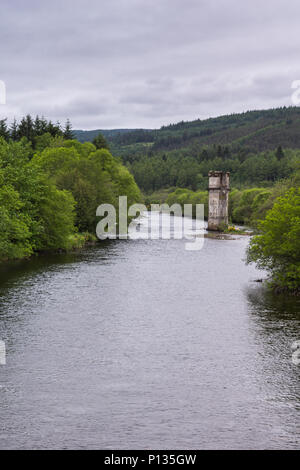 Fort Augustus, Scozia - Giugno 11, 2012: marrone residuo della torre di scomparso ponte su argento fiume Oich, fiancheggiata da verdi boschi lungo la sua riva Foto Stock