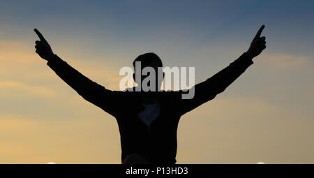 Silhouette di uomo a sunrise con le braccia alzate in segno di vittoria Foto Stock